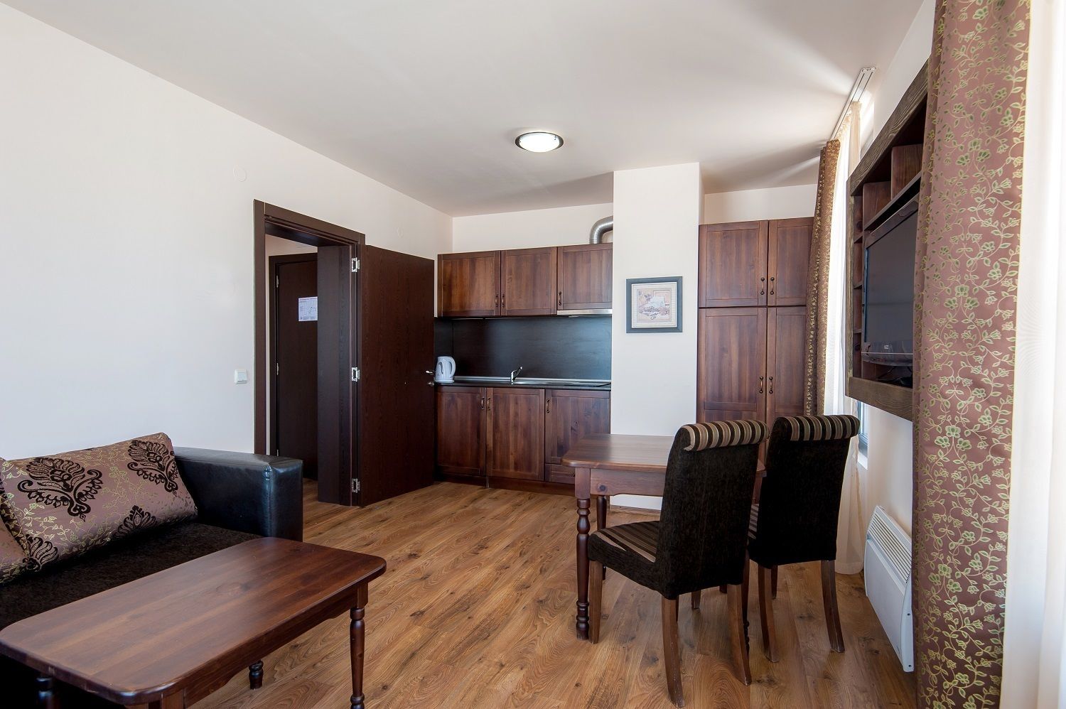 A compact living space with a kitchenette, a dining area with two chairs, a sofa, and a small table.