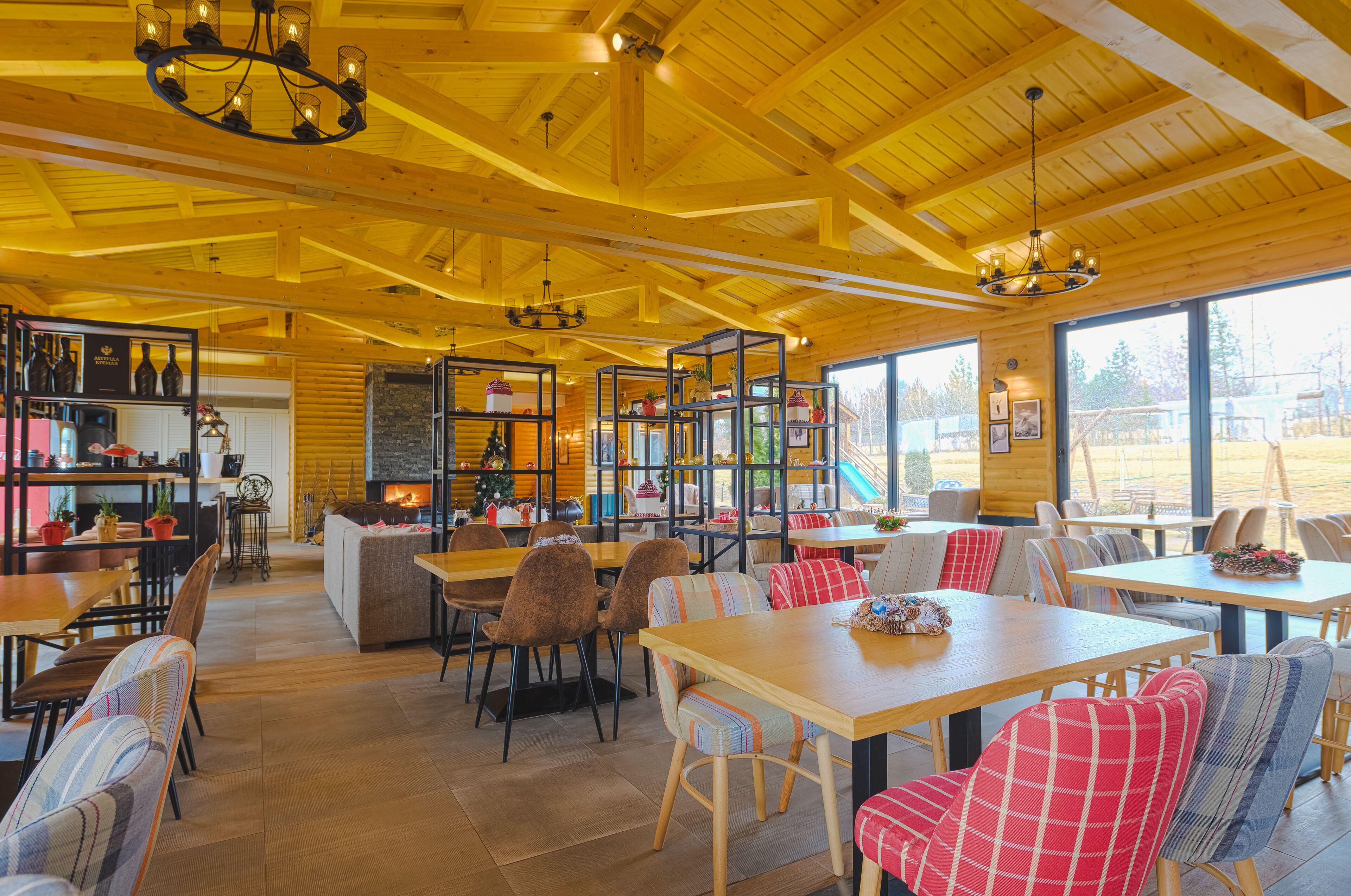 A cozy restaurant with wooden interiors, large windows, and a variety of seating arrangements.