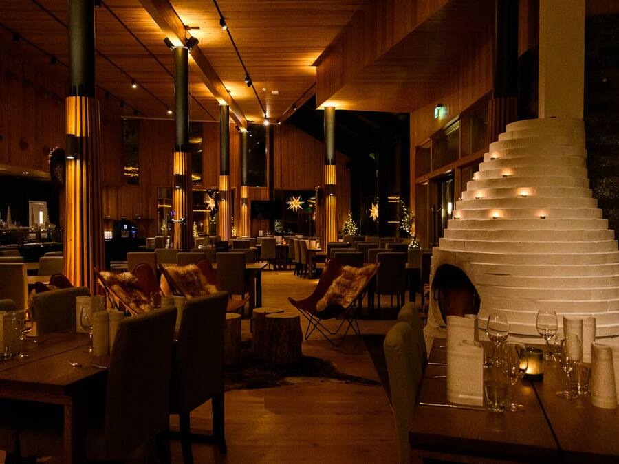 Un restaurante con interiores de madera, varias mesas y sillas.
