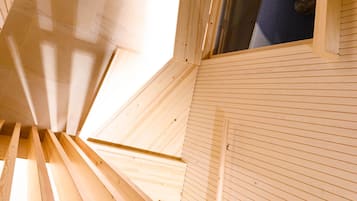 Una escalera de caracol con barandillas de madera y vistas a una habitación con ventana y lámpara en el techo.