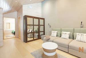 Una sala de estar moderna con un sofá, una mesa de centro de mimbre y un puerta corredera de cristal que da a un balcón.
