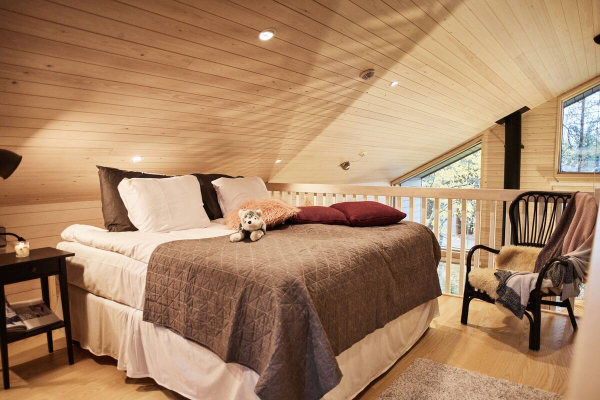 Een knus slaapkamer met een bed, een stoel, een nachtkastje en een raam.
