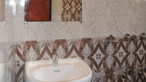 Un baño con un lavamanos blanco, un espejo y azulejos decorativos en las paredes.
