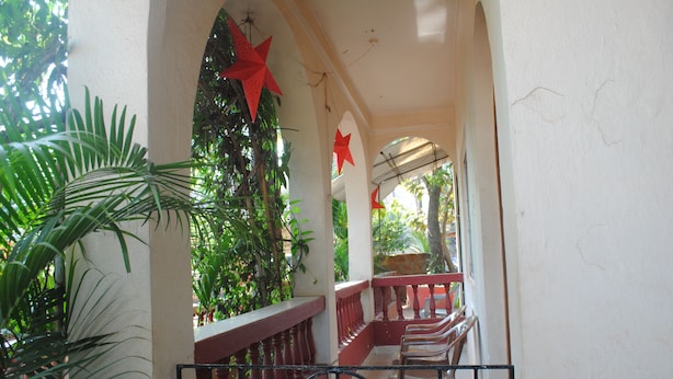 Un espacio al aire libre techado con un banco de madera, baranda y decoraciones con estrellas rojas.