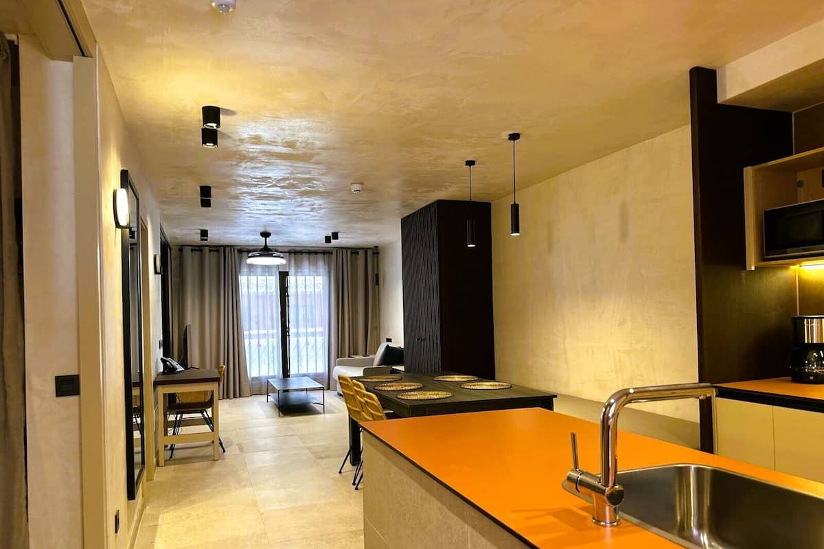 A modern kitchen with a central island, a built-in oven, and a stainless steel sink.