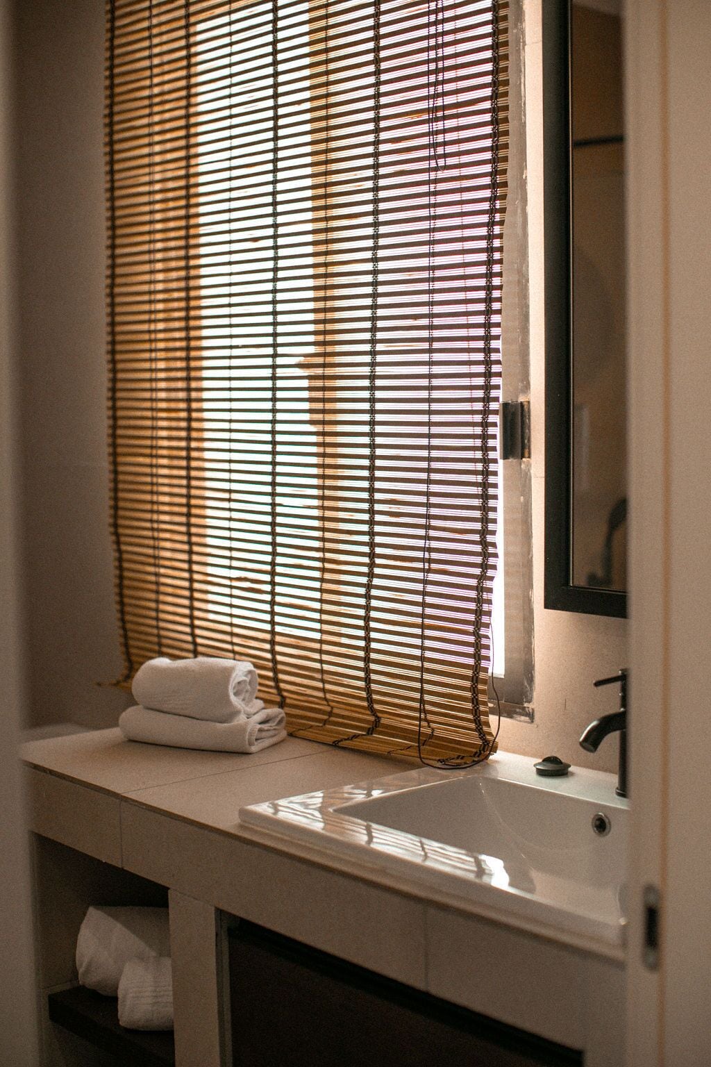 Un baño con lavamanos, espejo y toallero.