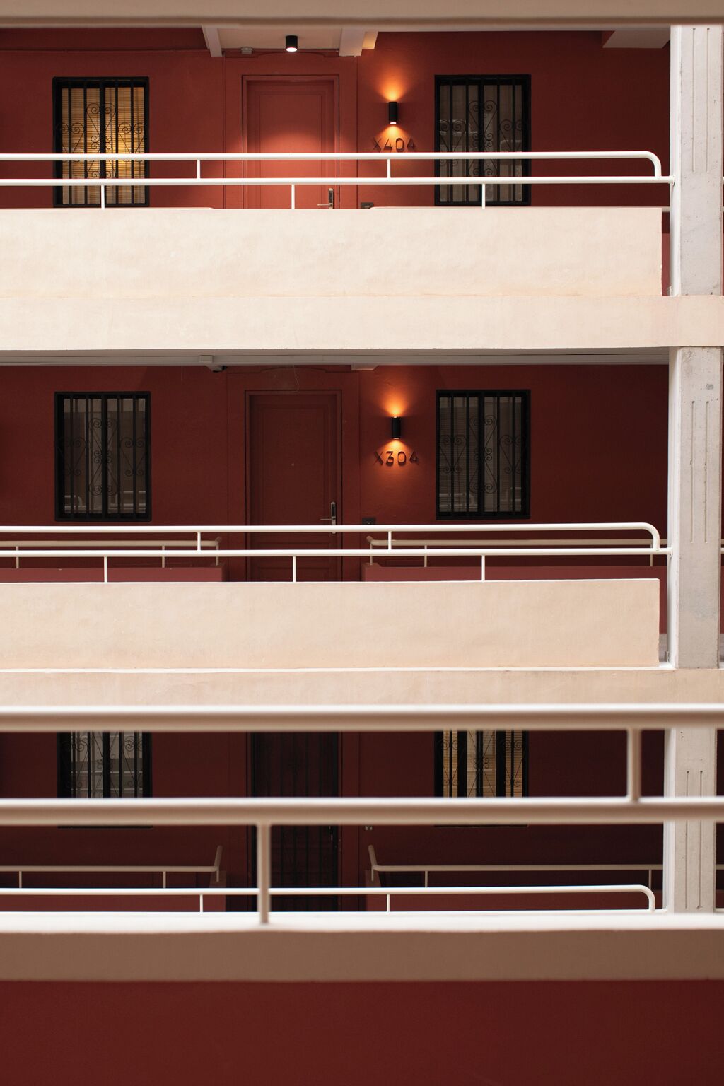 A multi-story building with balconies, each with a white railing and a door.