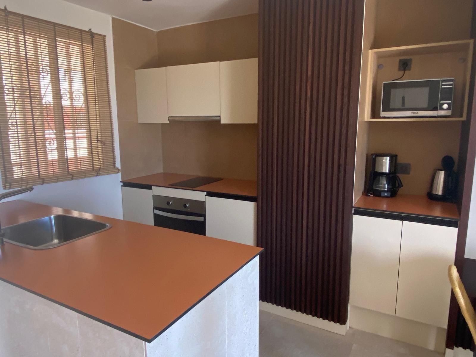 A compact kitchen with a sink, stove, and microwave.
