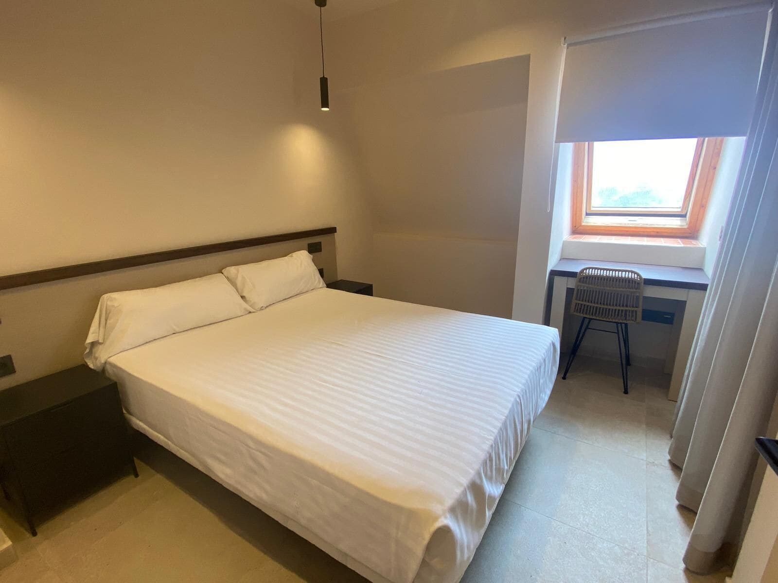 A hotel room with a single bed, a desk, and a chair.