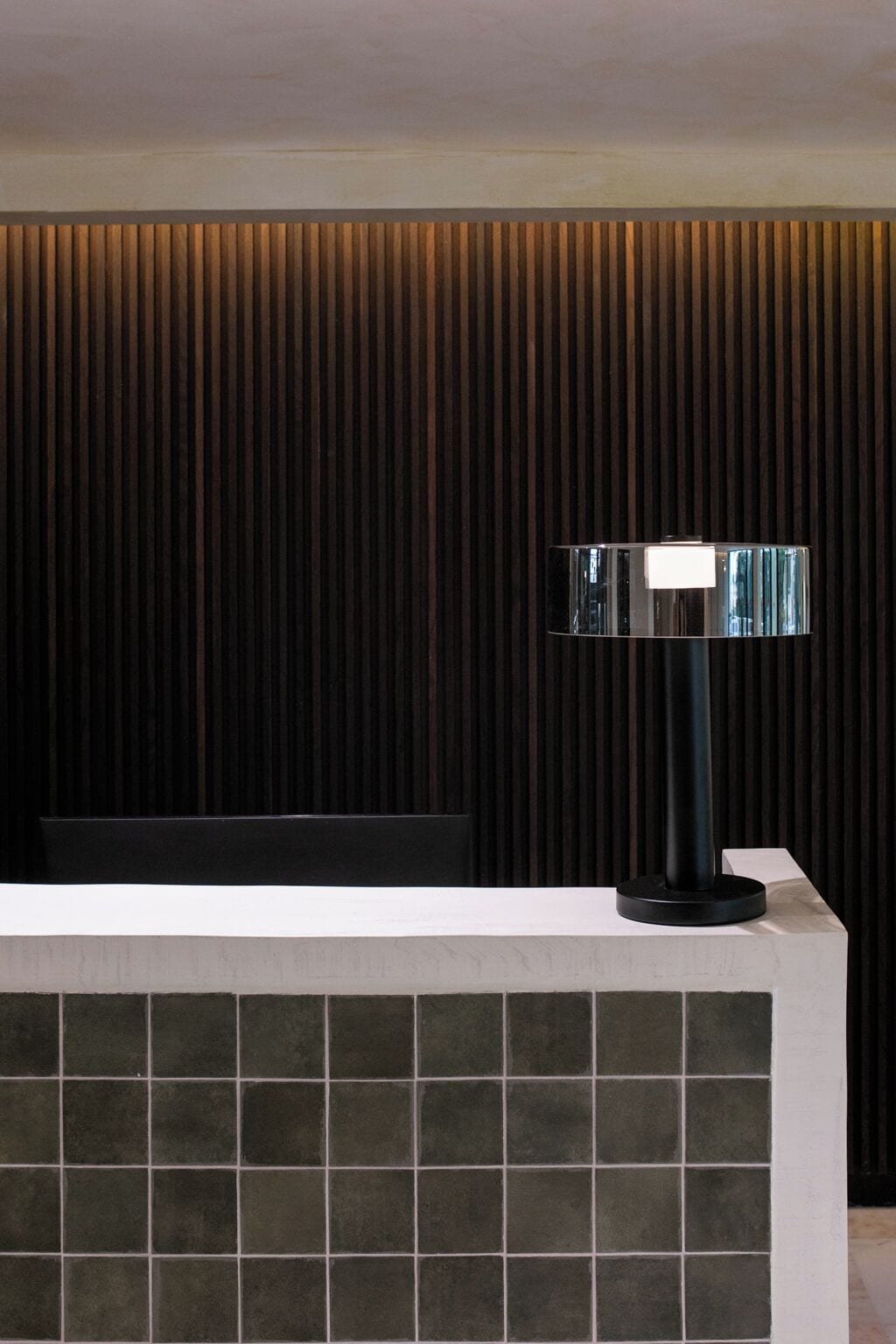 Un taulell de recepció de disseny modern, amb un mur de fusta fosca i un paviment de rajoles.