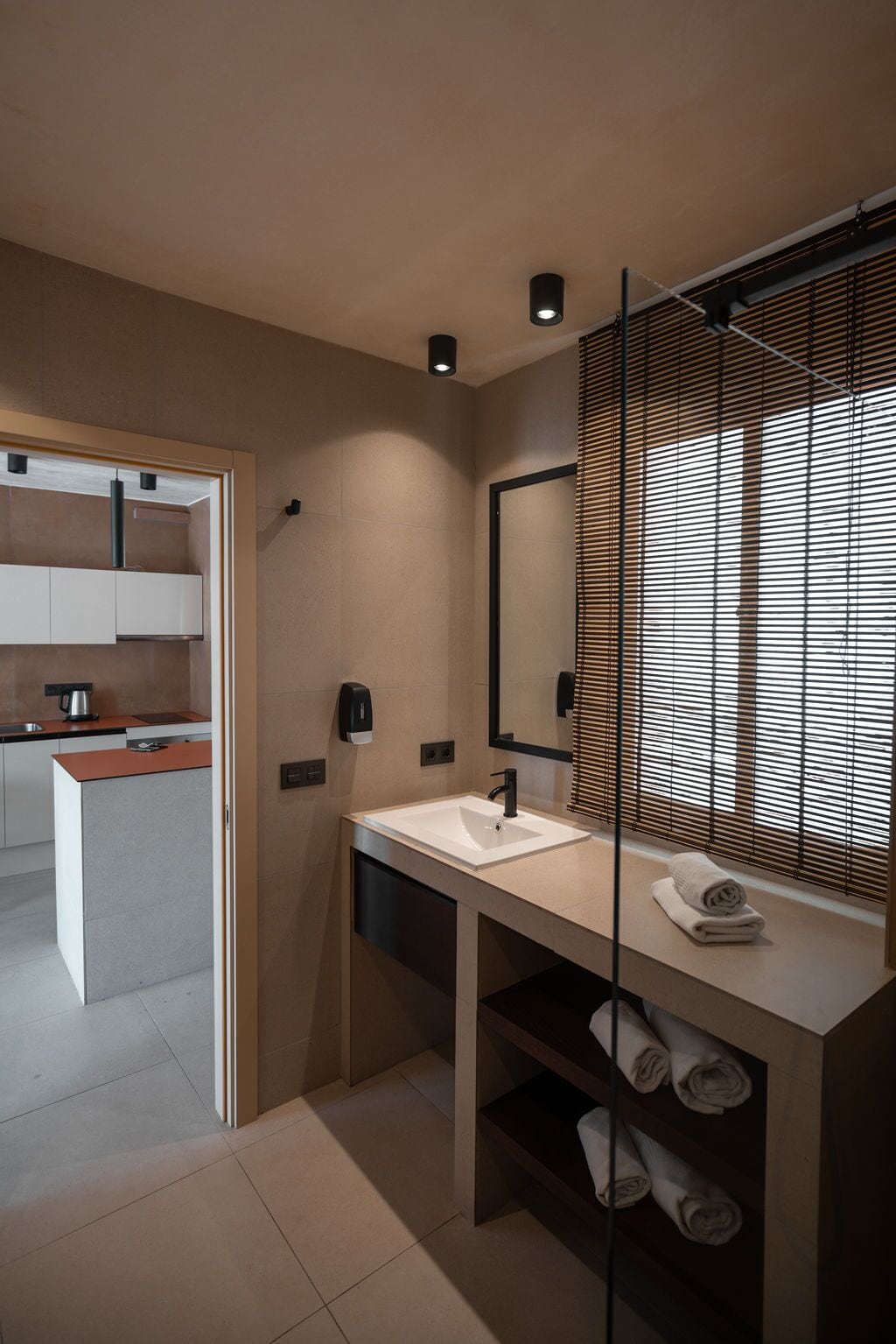 A modern bathroom with a large mirror, a white sink, and a towel rack.