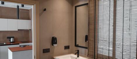 A modern bathroom with a large mirror, a white sink, and a towel rack.