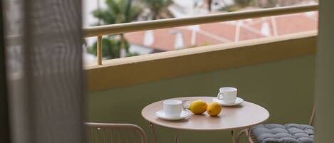 A balcony with a table set for two, two cups, and two lemons.