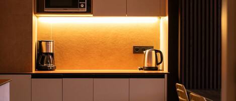 A compact kitchen with a microwave, coffee maker, and kettle on a countertop.