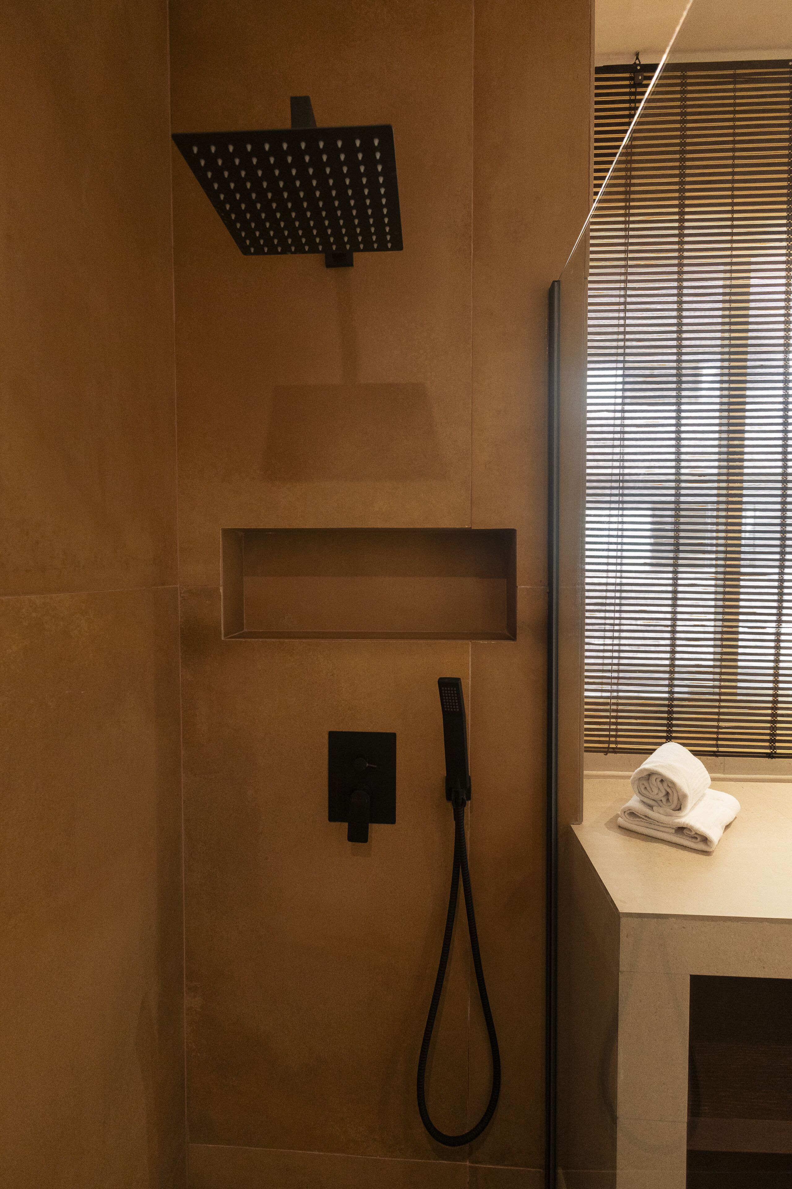 Une salle de bain moderne équipée d’une douche, d’un porte-serviettes et d’une fenêtre avec des stores.