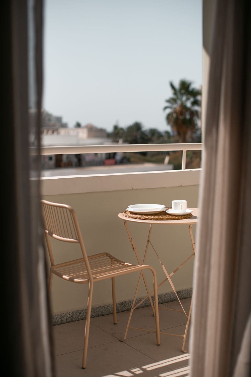 Ein Balkon mit einem Korbstuhl, zwei Stühlen und Blick auf die Stadtlandschaft.