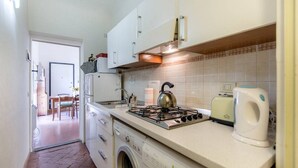 A compact kitchen with a gas stove, a washing machine, and a toaster. - Appartamento Dante (Florence)