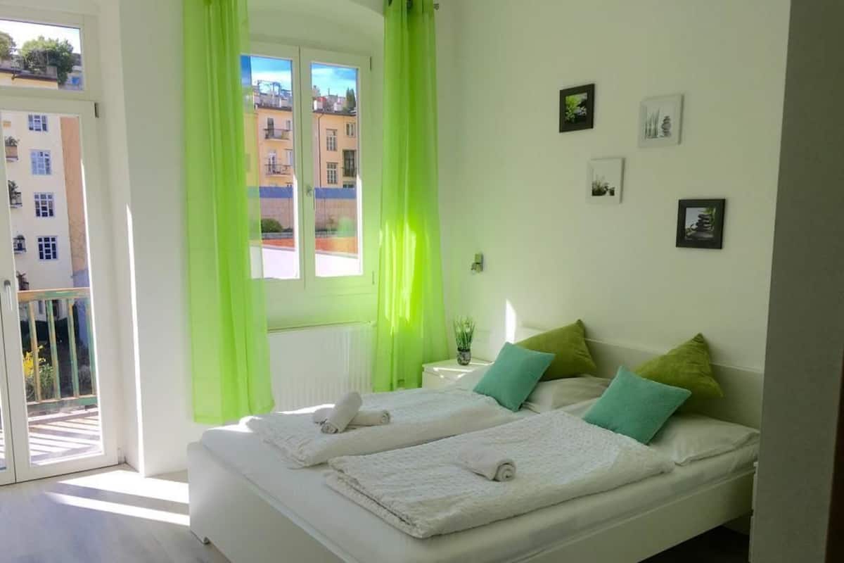 Un dormitorio con dos camas, un balcón y vistas a edificios.