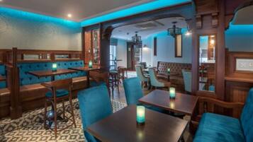 Un restaurante con cabinas y mesas, asientos tapizados en azul y un suelo con diseño.