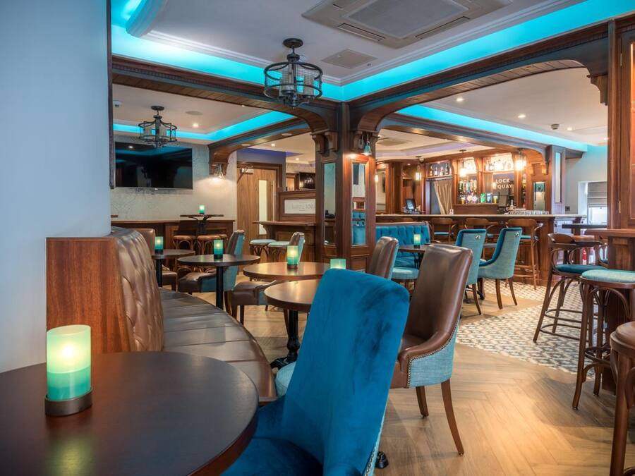 A restaurant with wooden furniture, a bar area, and a chandelier.