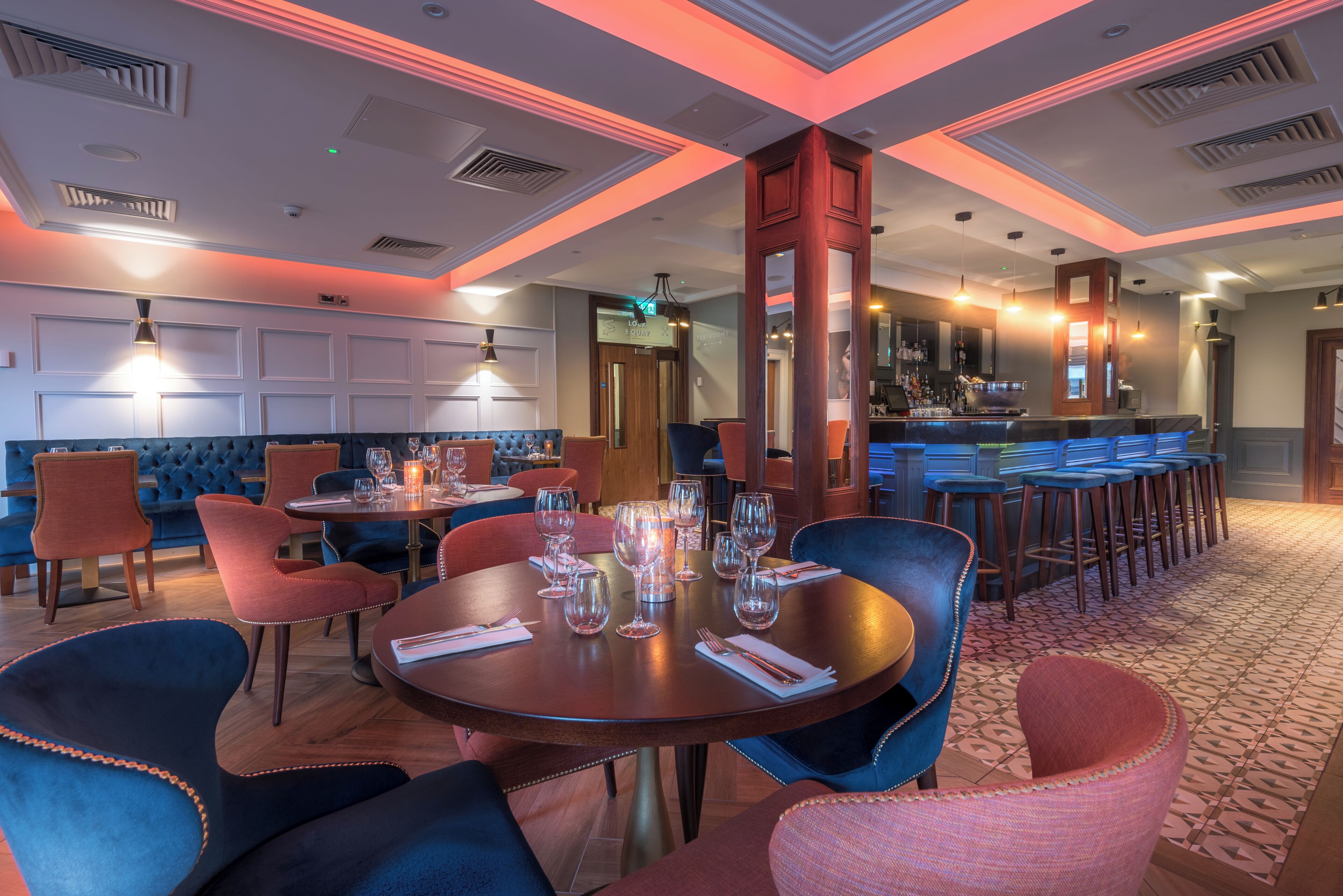 A restaurant with round tables, bar stools, and a bar area.