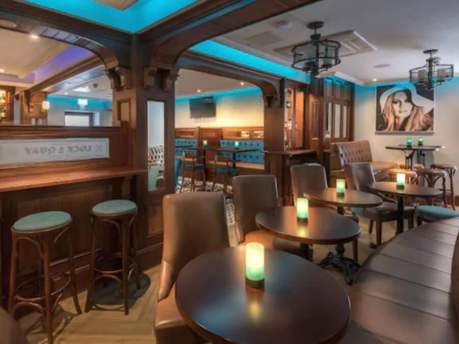 Un interior de restaurante acogedor con mobiliario de madera, una zona de bar y un mural en la pared.