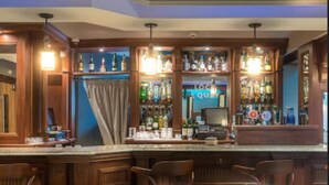 A bar area with wooden bar counters, blue cushioned chairs, and a variety of liquor bottles. - Shipquay Boutique Hotel (Londonderry)