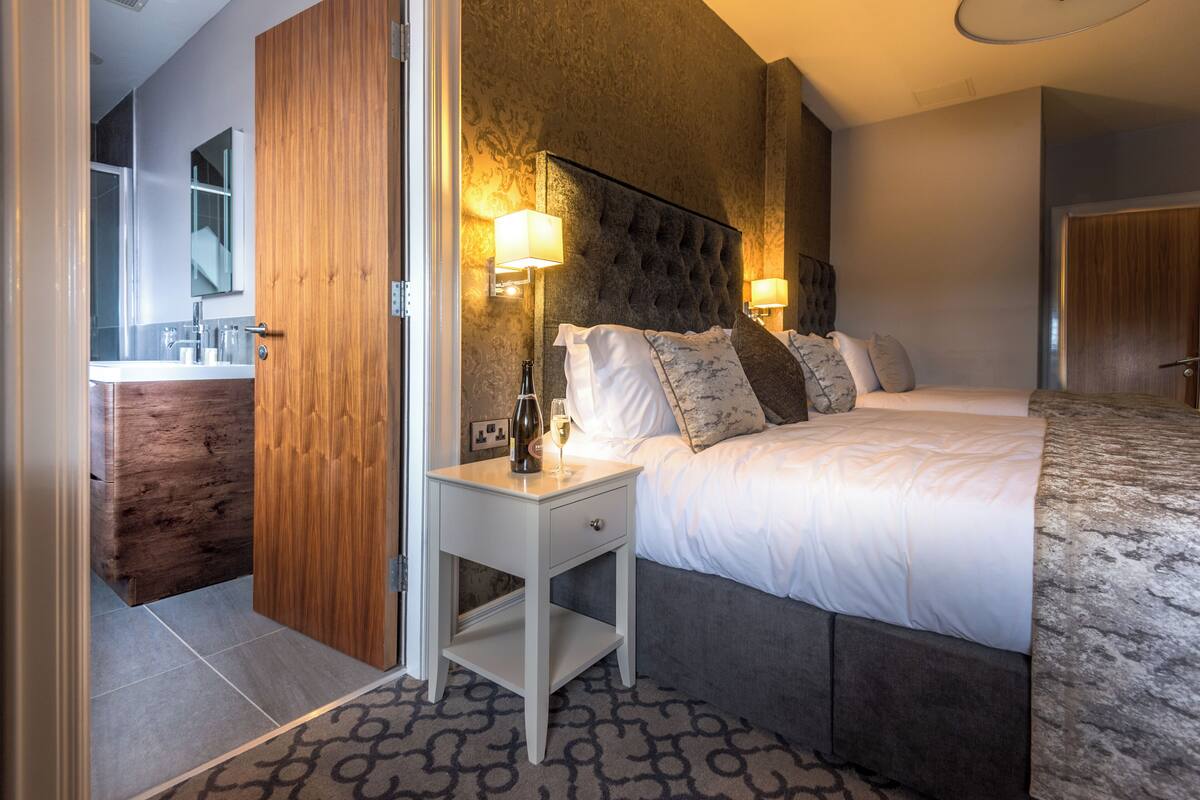 Un dormitorio moderno con una cama grande, lámparas de noche, una mesita de noche y una puerta de madera.
