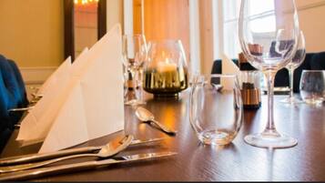 A dining table set with white napkins, silverware, and clear wine glasses.