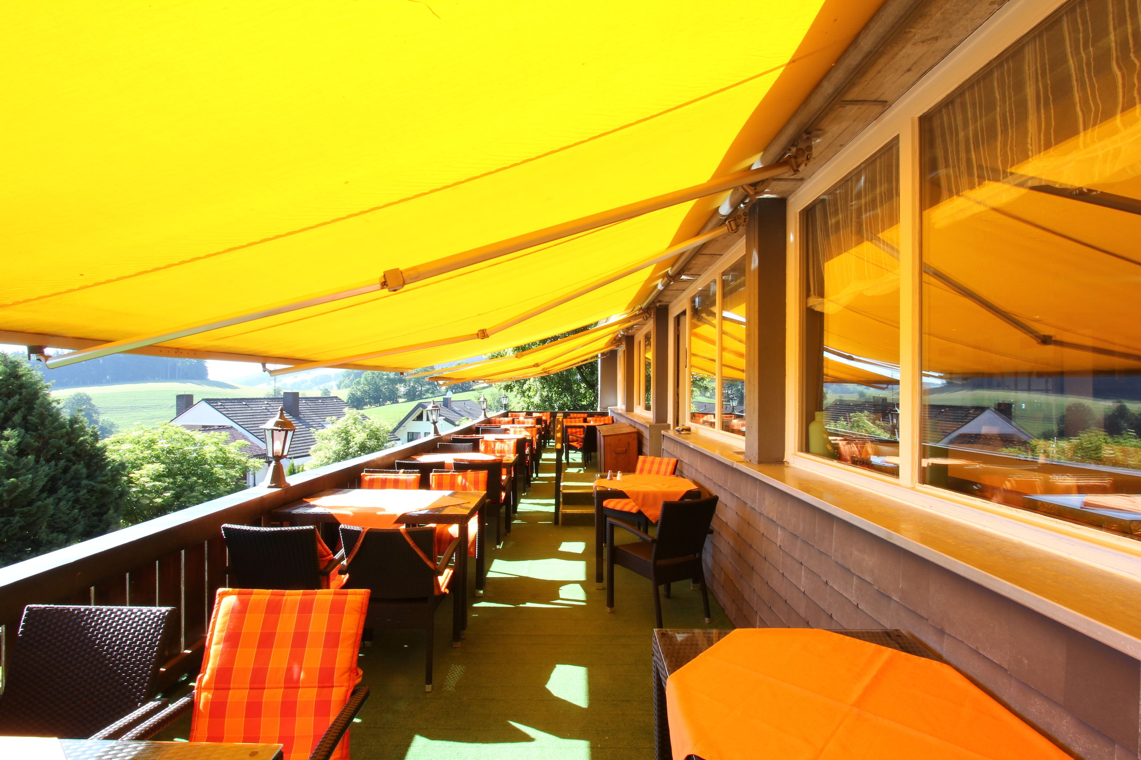 An outdoor dining area with yellow canopies, wooden tables, and chairs.