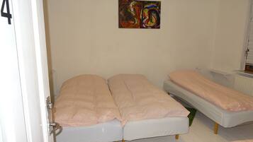 A room with two single beds, a radiator, and a painting on the wall.