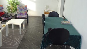 A modern room with a green table, white chairs, a TV, and a plant. - Pasescia Bed and Breakfast (Kolind)