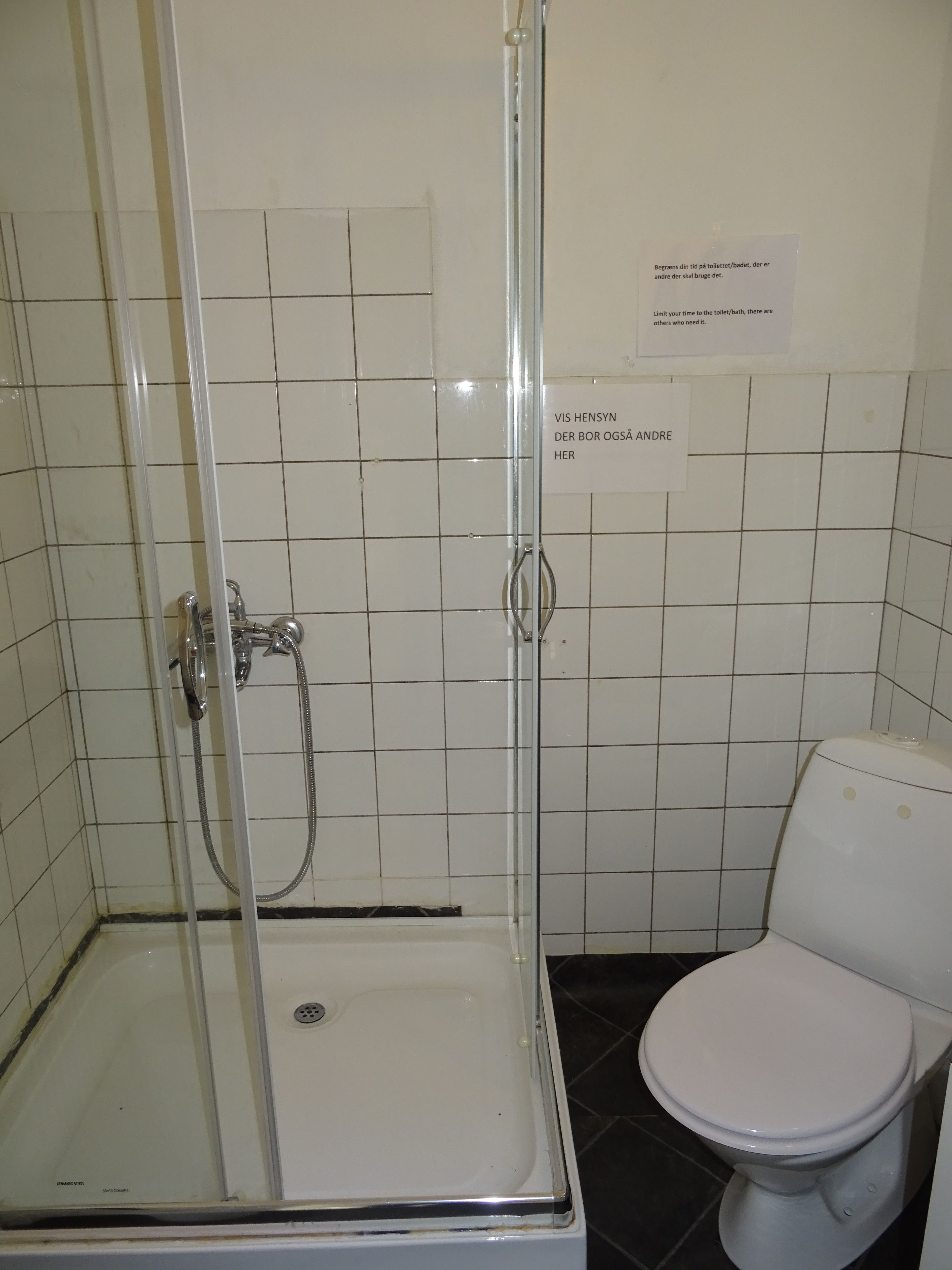 A bathroom with a glass-enclosed shower, a white toilet, and tiled walls.