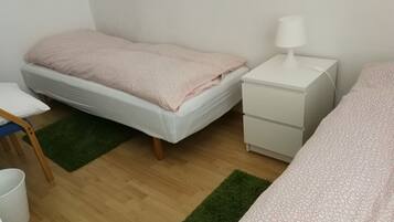 A bedroom with a bed, bedside table, lamp, and a small desk with chair.