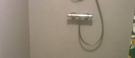 A small, enclosed shower area with a white shower seat and a handheld showerhead.