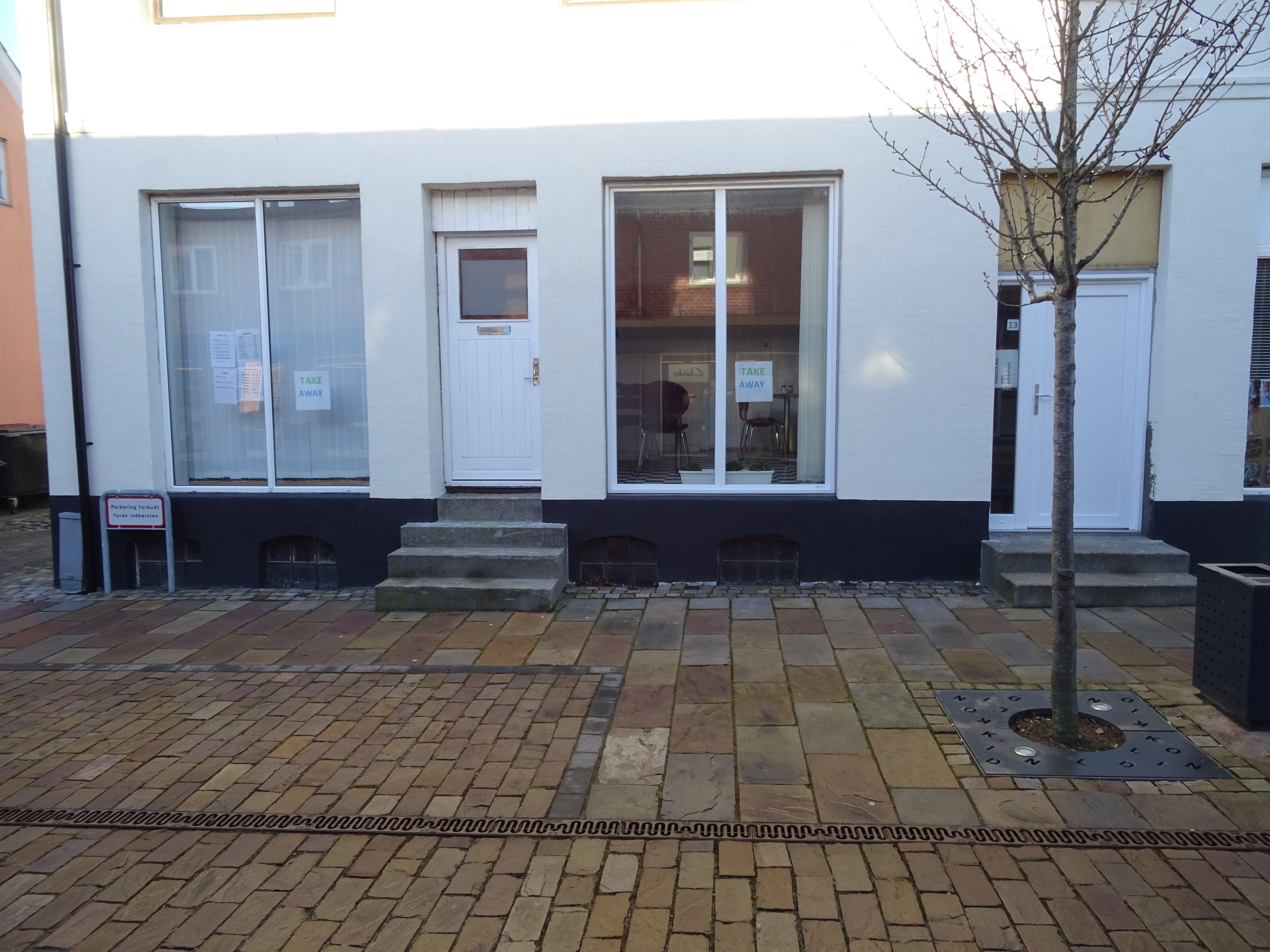 A building with large windows, a white door, and a sign indicating parking is not available.