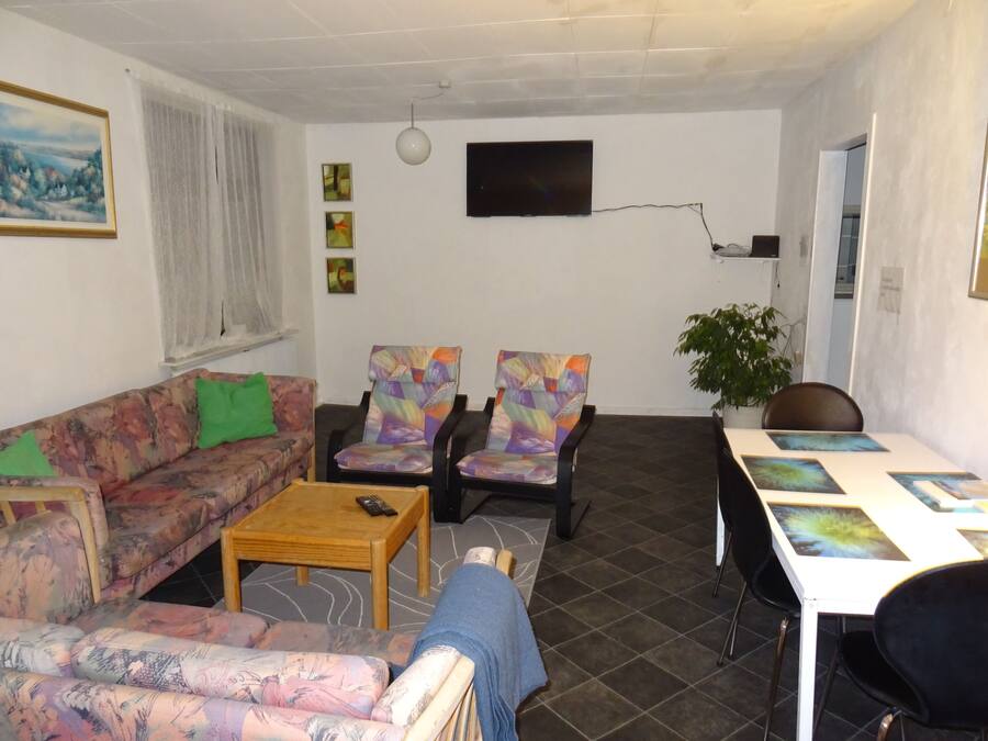 A living room with a sofa, two armchairs, a coffee table, and a TV.