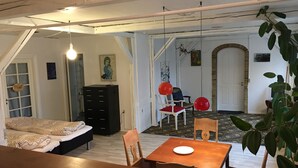 Ett rum med en säng, ett skrivbord, en stol och ett matbord. En trappa leder till ett annat rum.