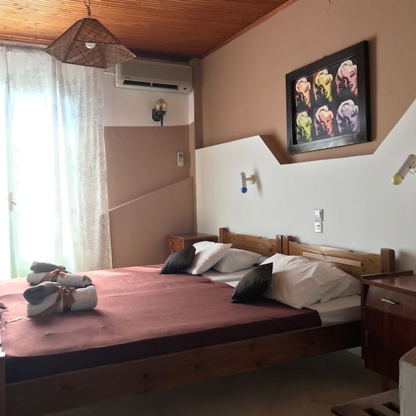 Een slaapkamer met een houten bed, een schilderij aan de muur en een raam met gordijnen.