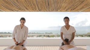 Una sesión de terapia de masajes en un balcón con vistas al mar y edificios.