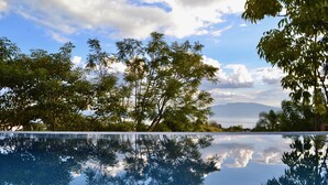 Una piscina cristalina que refleja árboles y un cielo nublado.