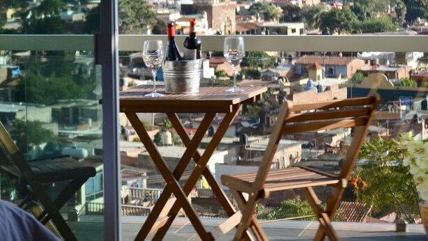 Un balcón con una mesa, dos sillas, una botella de vino y una copa.