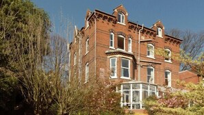 A large, historic brick building with multiple windows and a prominent bay window. - Hillcrest Hotel (Lincoln)