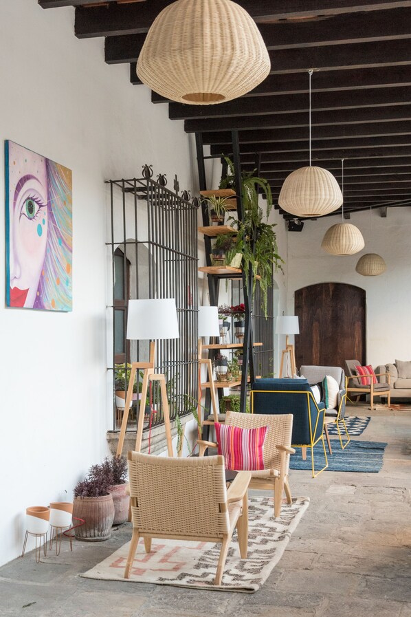Un interior acogedor con muebles de mimbre, un cuadro grande y lámparas colgantes.