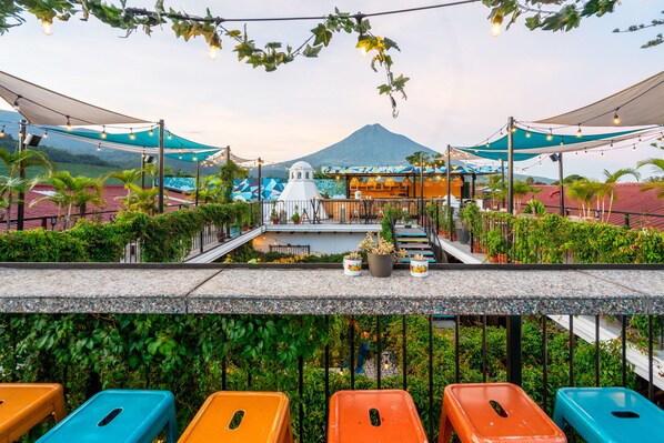 Une terrasse avec des sièges extérieurs, une vue sur une montagne et un espace restaurant doté d’une structure en forme de dôme blanc.