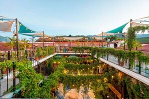 Un jardín en la azotea con plantas en macetas, una piscina y mobiliario de exterior.