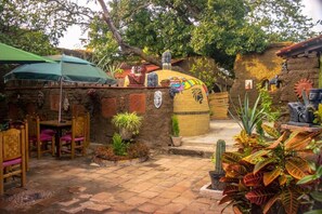 Un espace extérieur aménagé en terrasse, avec un sol en pierre, des meubles en bois et diverses plantes en pot.