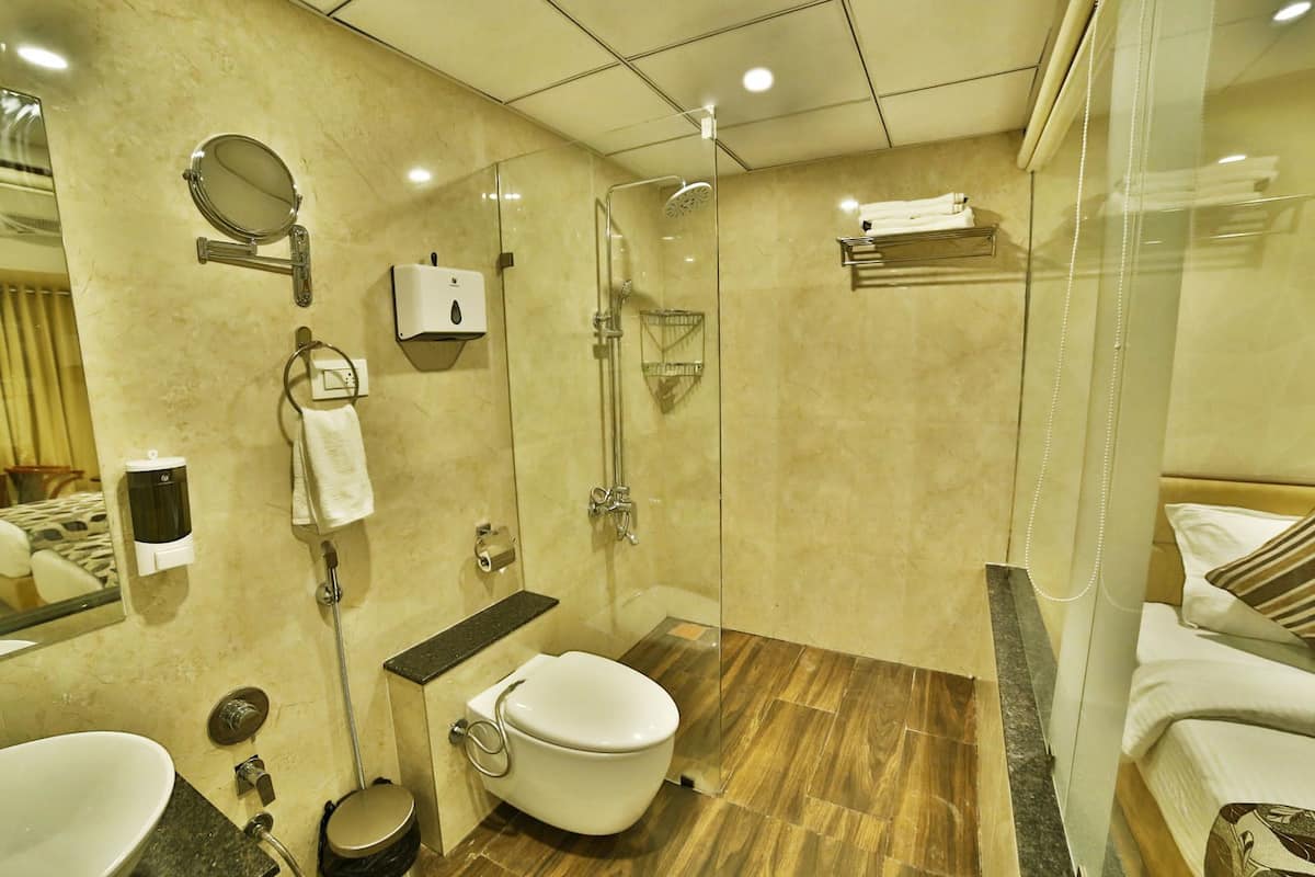 A modern bathroom with a glass shower enclosure, a toilet, a sink, and a mirror.