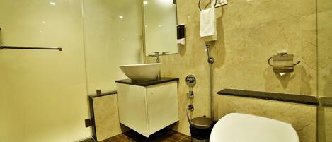 A modern bathroom with a glass shower enclosure, a white sink with a vessel basin, a toilet, and a towel rack.