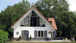 A modern two-story house with a white facade, a red-tiled roof, and a large glass window. - La Garonde (Berthen)